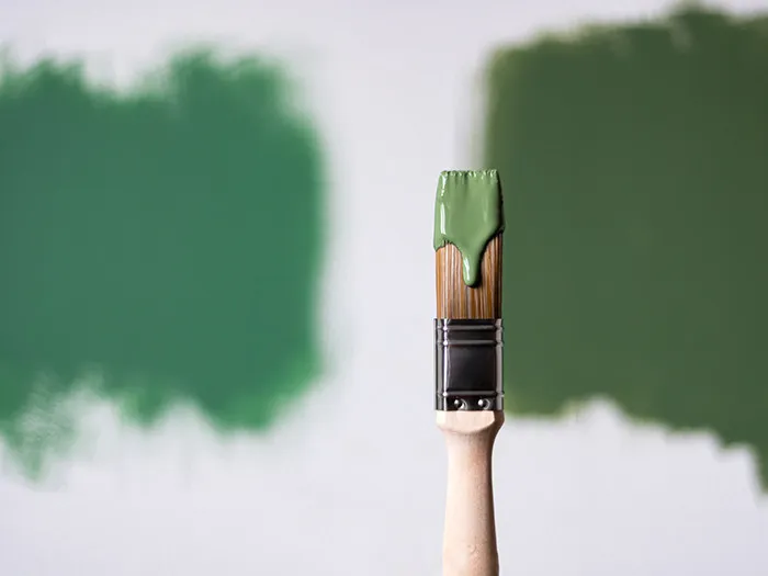 Paintbrush with green paint dripping, demonstrating a creative way to deliver satisfaction in customer staff interactions.