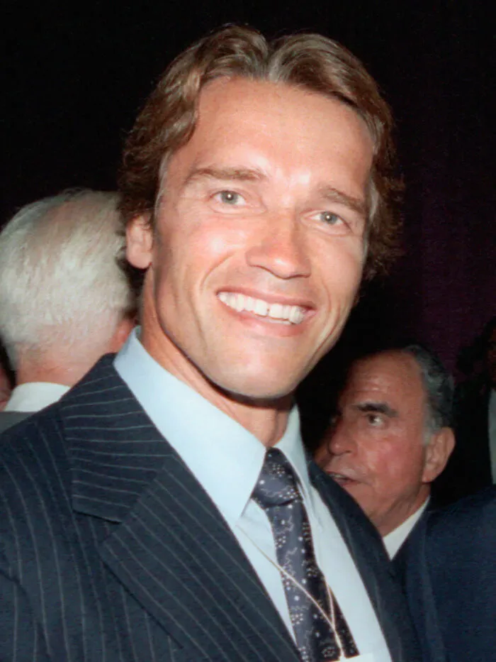 Smiling man in a dark pinstripe suit and patterned tie, representing notable moments from the year you were born.