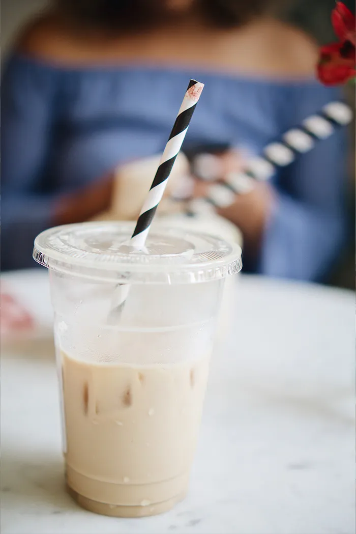 Iced coffee in a plastic cup with a black and white striped straw, highlighting rude customers who learned the hard way.