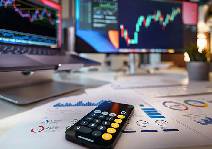 Calculator on printed charts and graphs in front of computer screens showing data, related to scientists' biggest theories.