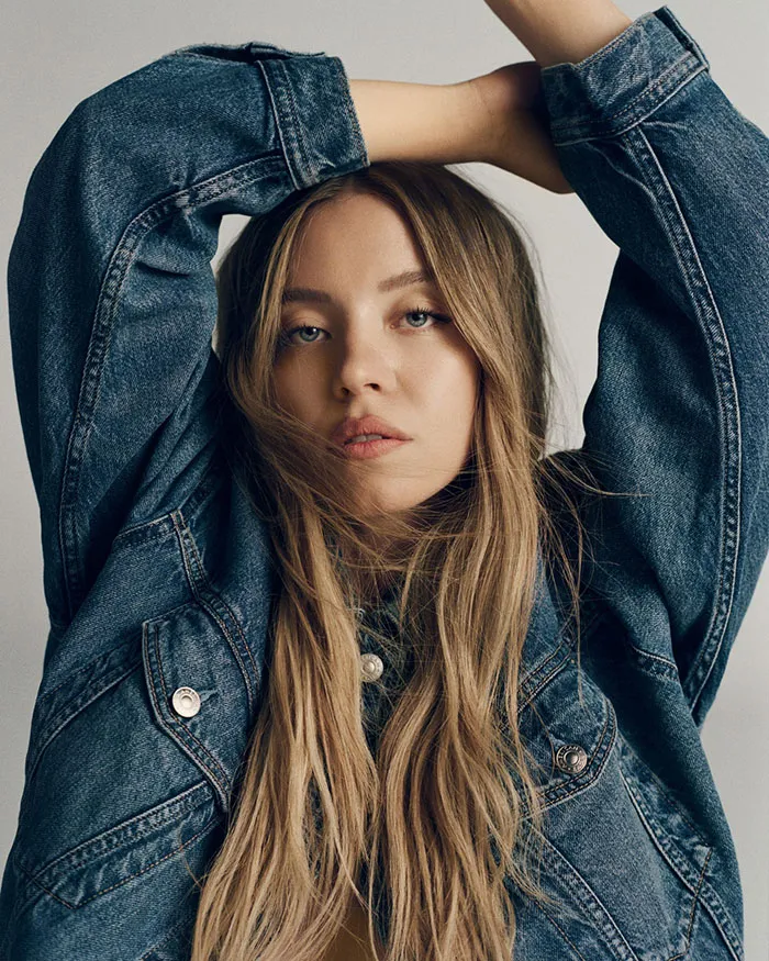 Young woman with long hair wearing a denim jacket, posing with arms raised, illustrating marketing fails concept.