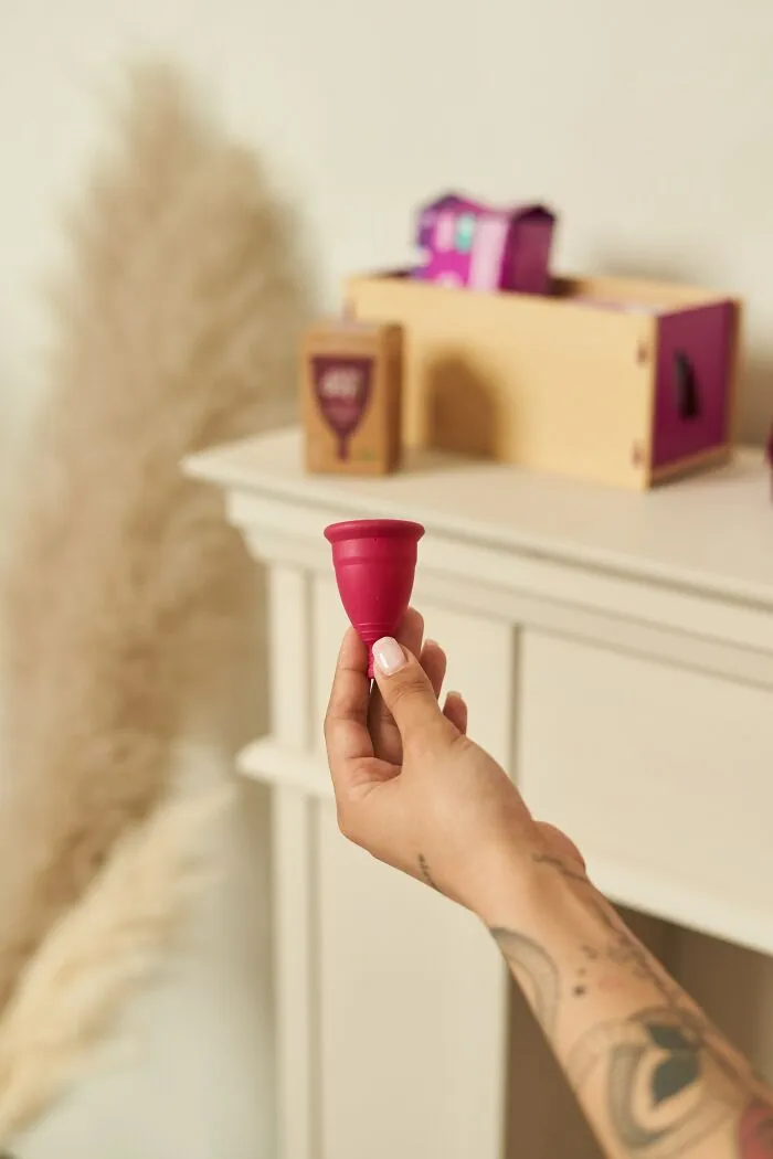 Hand holding a menstrual cup, representing advice for dads raising daughters. Eco-friendly period care.