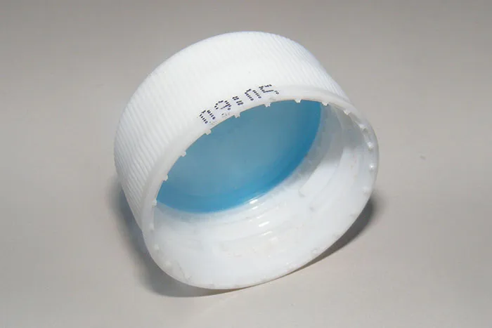 A white plastic bottle cap with a blue interior, lying on its side. This photo will take you down memory lane.
