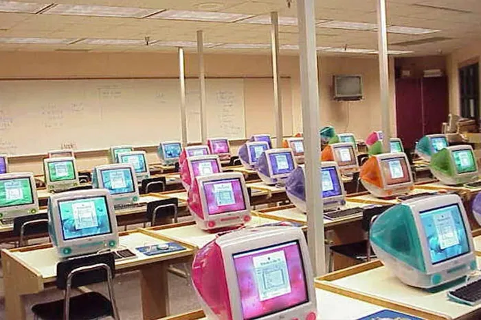 A classroom filled with rows of colorful, translucent iMac G3 computers, evoking a trip down memory lane.