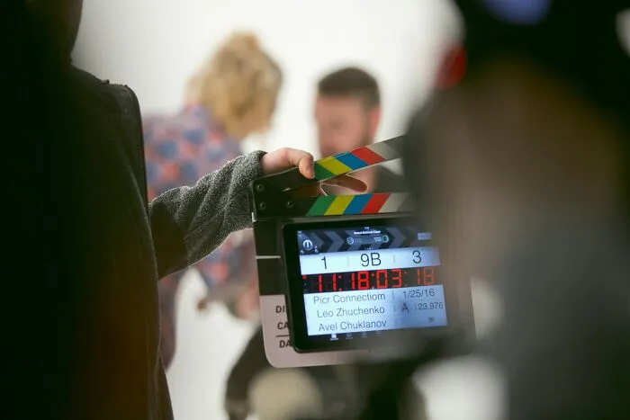 Film crew member holding a clapperboard on set, capturing a scene related to betrayal and shock themes.