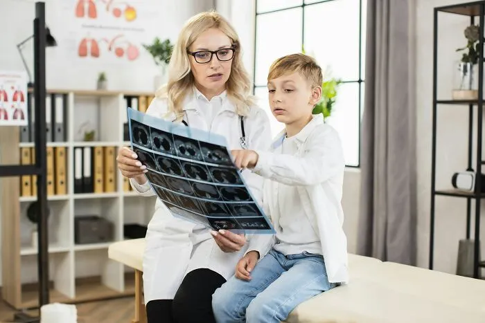A doctor and a young patient reviewing an X-ray, illustrating stories of patients being ignored in emergencies.
