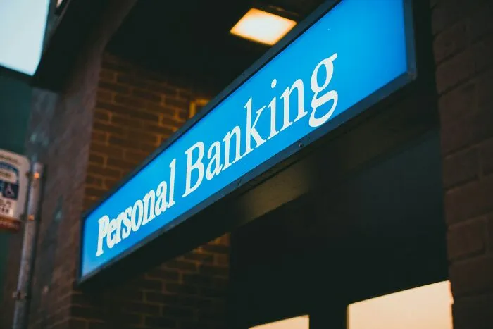 Blue illuminated personal banking sign mounted on a brick building, highlighting smart banking and financial intelligence.