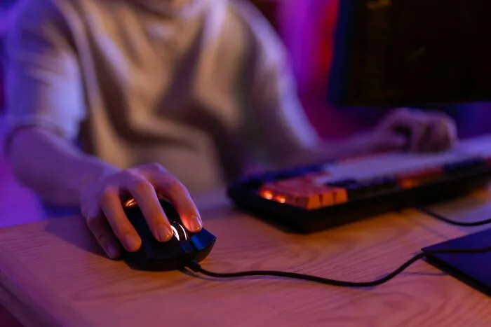 Person using a computer mouse and keyboard in dim lighting, illustrating being a good person facing total betrayal.