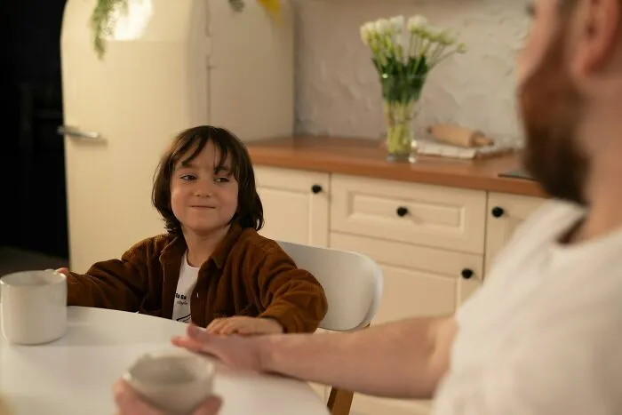 A young girl smiling at her dad in a kitchen, discussing advice for dads raising daughters.