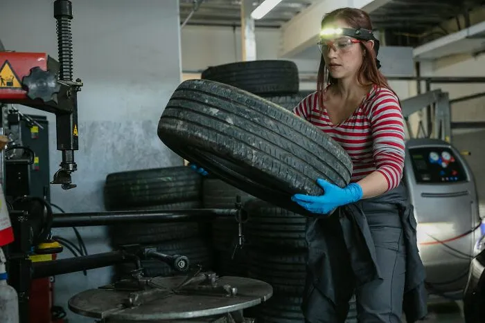 A woman with a headlamp and safety glasses handles a tire. This image reminds us of advice for dads raising daughters.