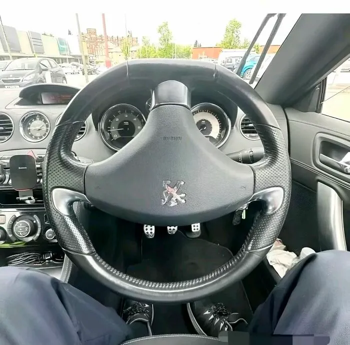 View of a car interior focusing on the steering wheel, pedals, and dashboard demonstrating pareidolia in everyday objects.