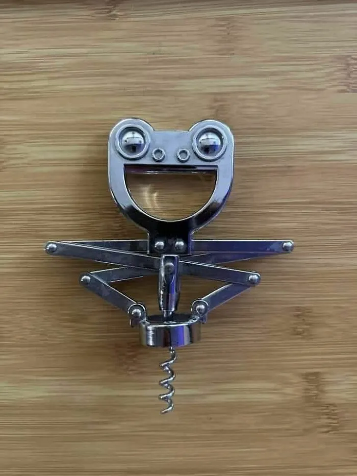 Metal corkscrew on wooden surface resembling a smiling face, an example of pareidolia captured in a photo.