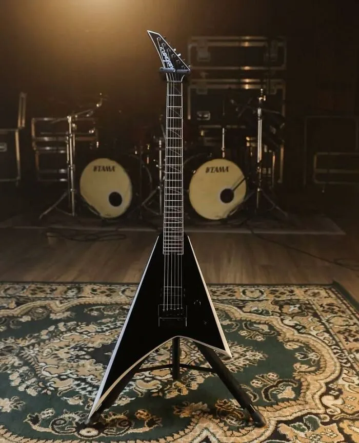 Black electric guitar appearing like a face with drum set eyes in the background, showcasing pareidolia in music gear.