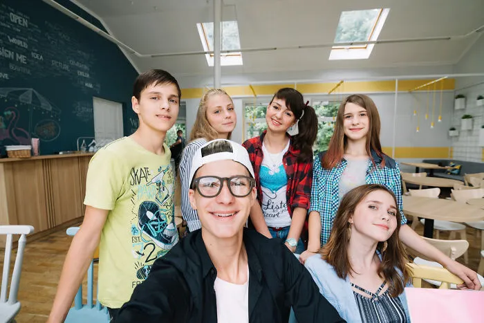Six smiling young people posing for a group photo, representing students navigating absurd rules in schools.