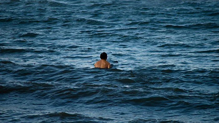 Person swimming alone in deep water emphasizing safety tips for everyone to know while in open water.