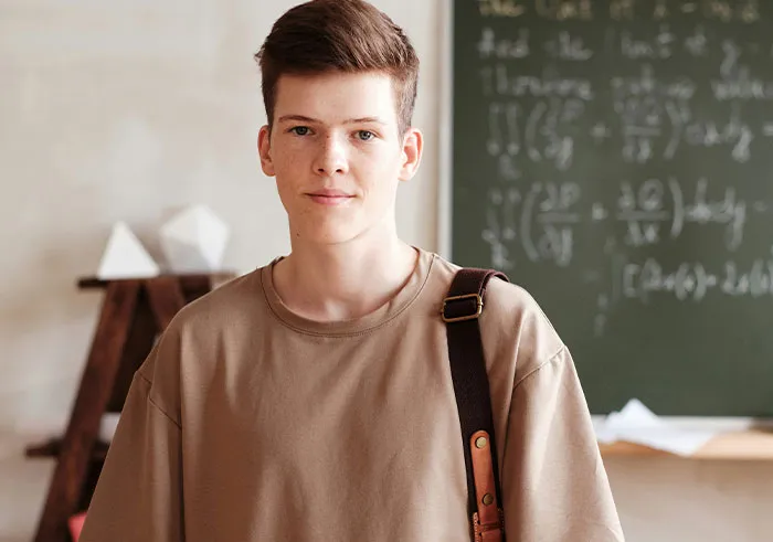 Young man with thoughtful expression by a math chalkboard, embodying profound intelligence.