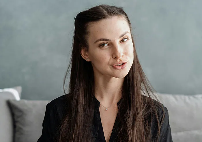 Young woman with long dark hair and thoughtful expression showing subtle displays of intelligence indoors