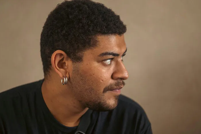 Young man with hoop earrings looking to the side, illustrating subtle and interesting displays of intelligence in a thoughtful pose.
