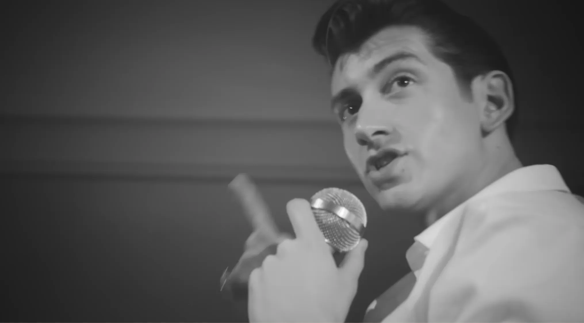 Black and white close-up of a lead singer holding a microphone, looking up while performing. Music Challenge.