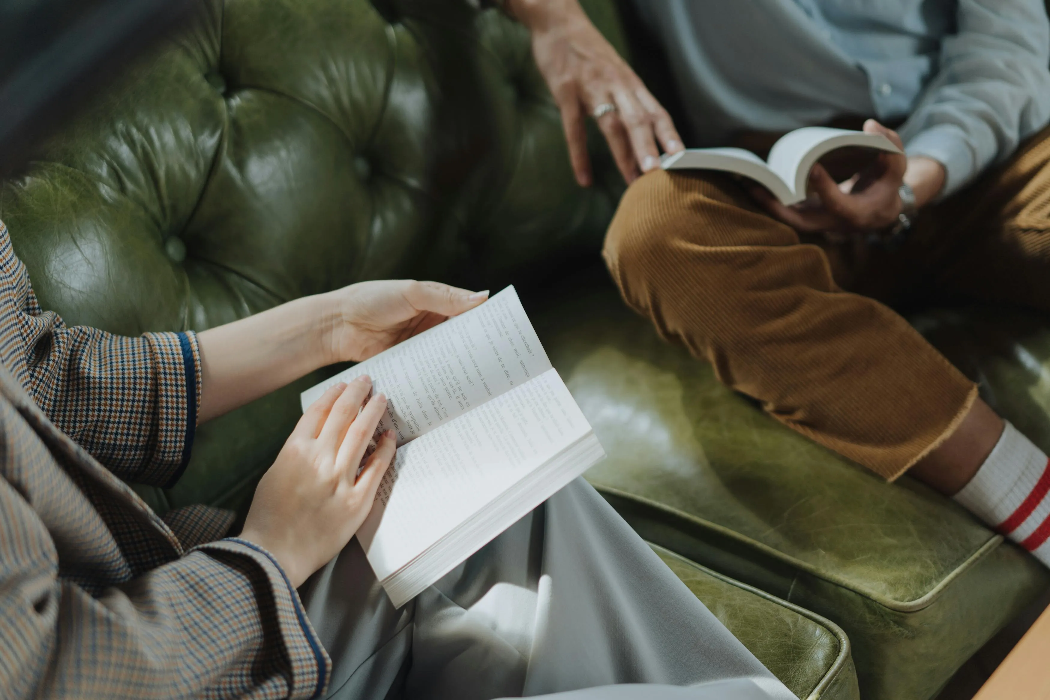 Two people on a green leather couch reading books, discussing philosophy and what subject to retake.