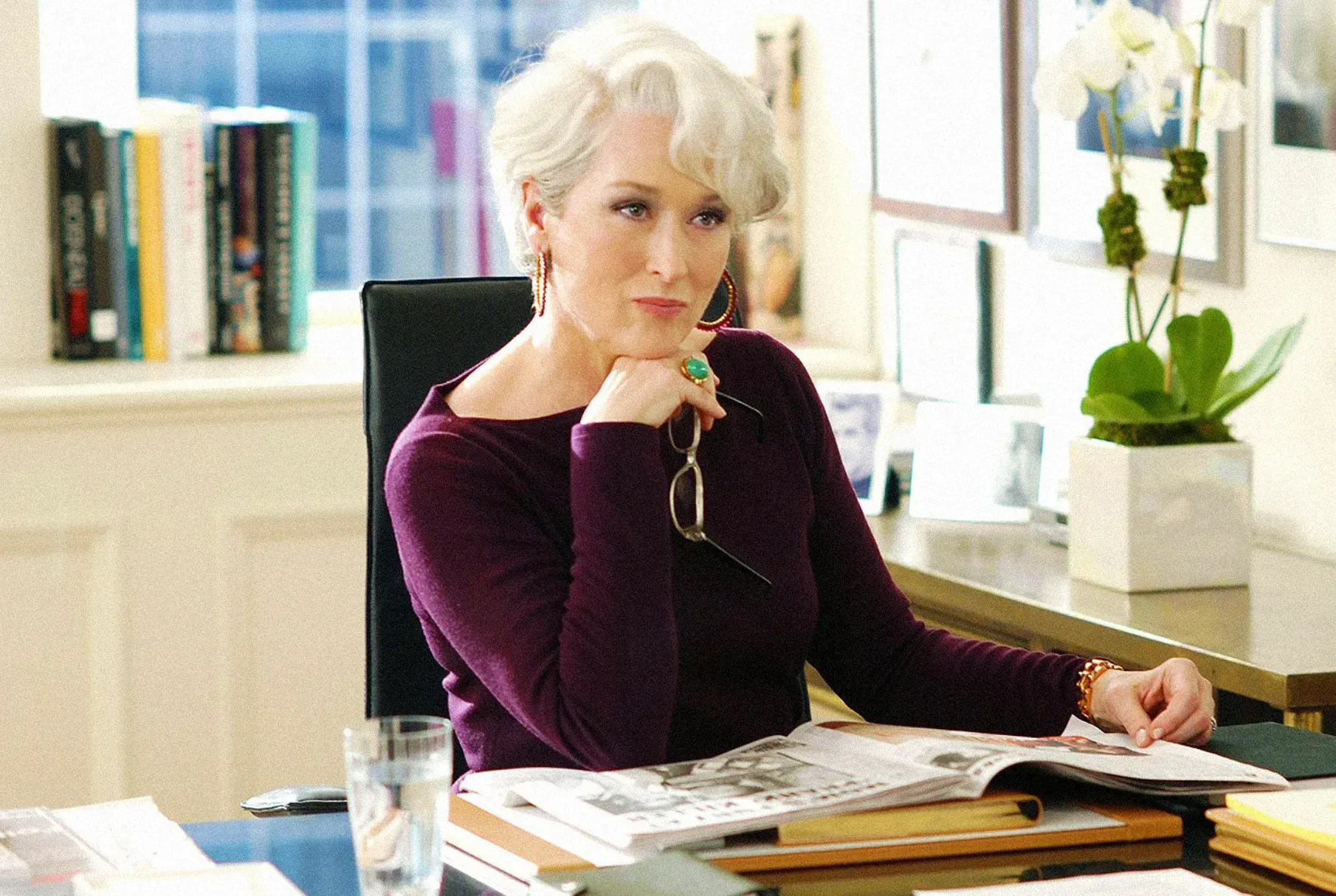 Miranda Priestly from The Devil Wears Prada, a fictional mentor, sitting at a desk with an open magazine.