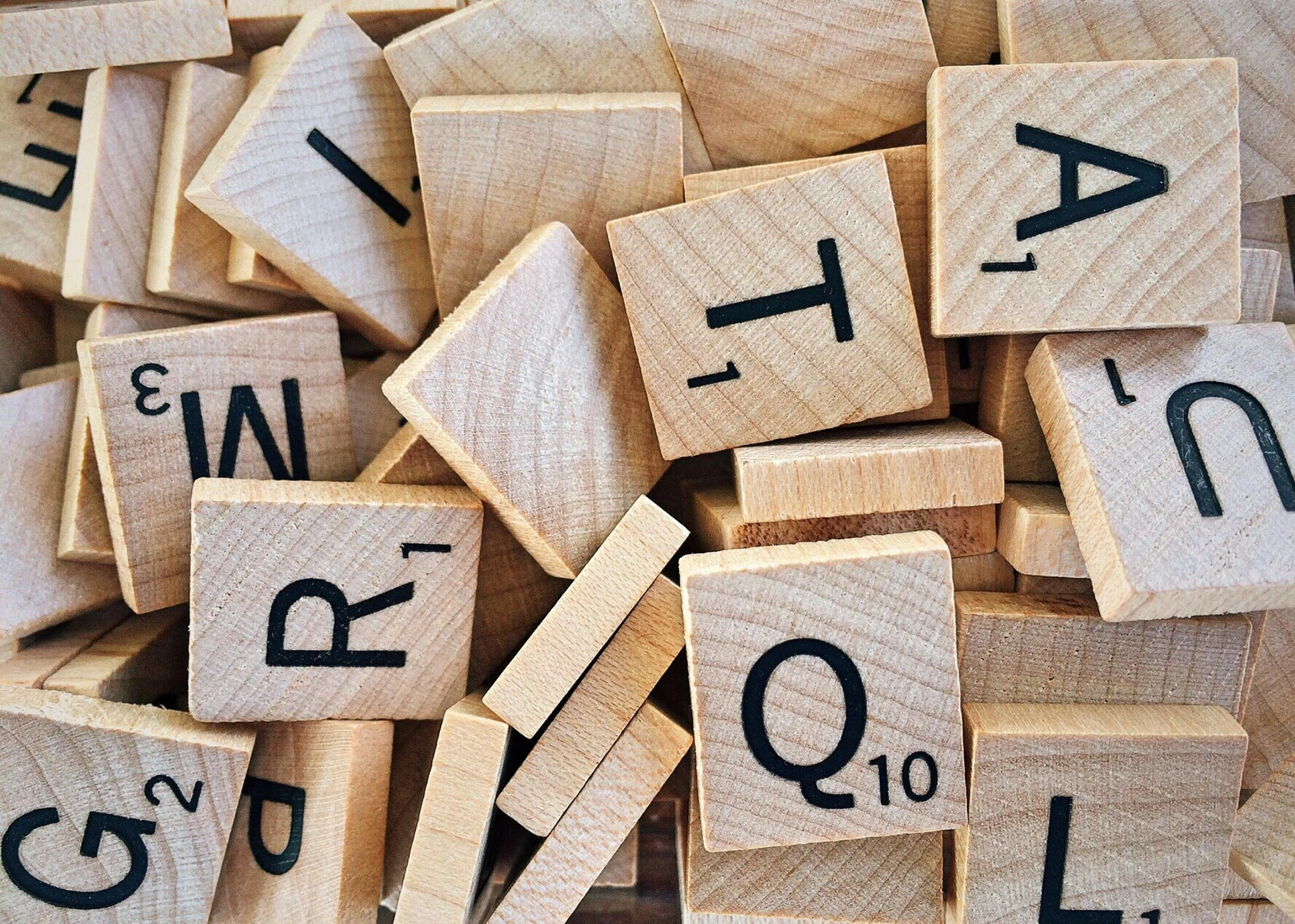 A close-up of scattered Scrabble tiles, featuring letters like Q, T, A, and R, ready for a classic board game night.