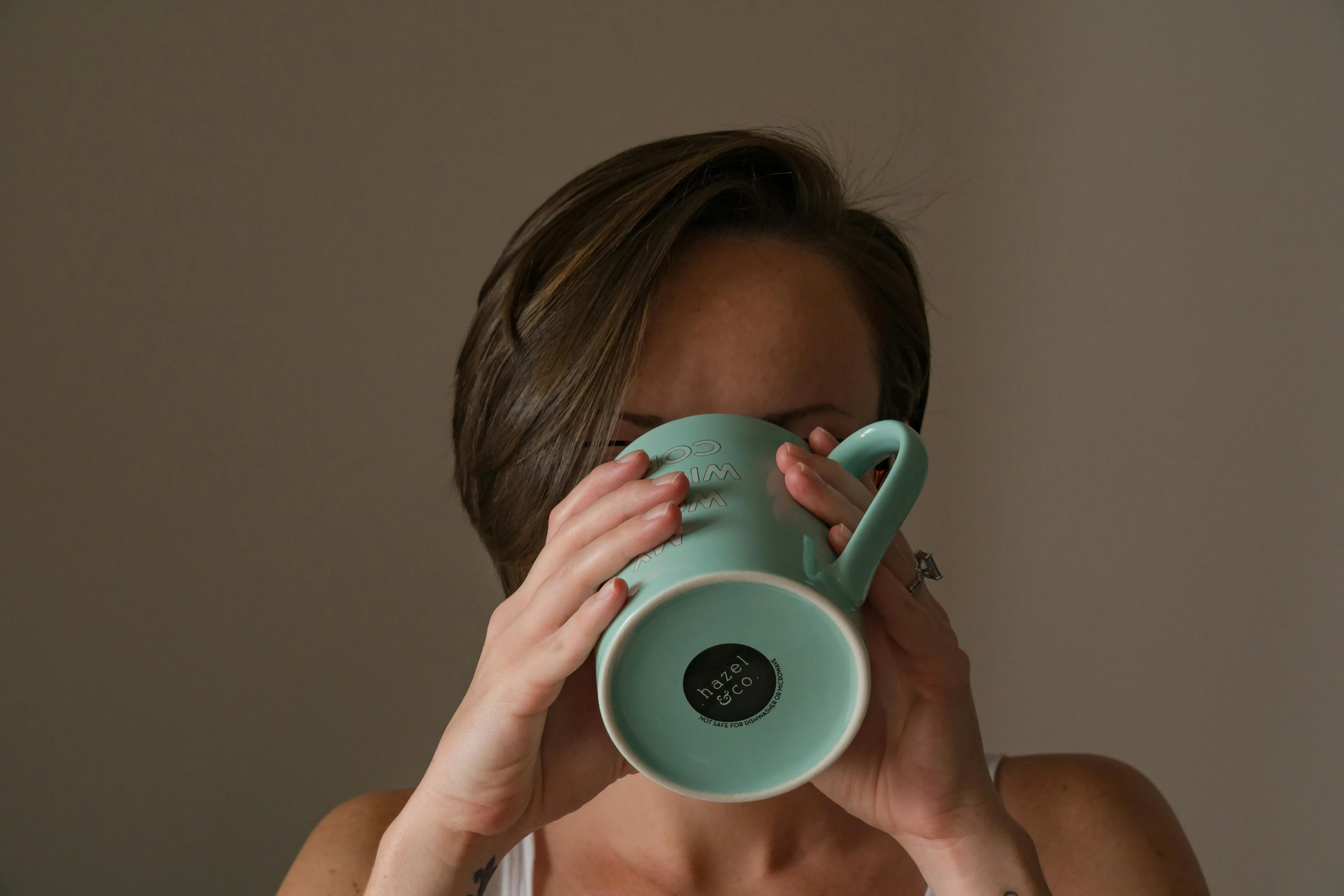 A person with short brown hair holding a light blue custom coffee mug. Focus on self-sabotage patterns.