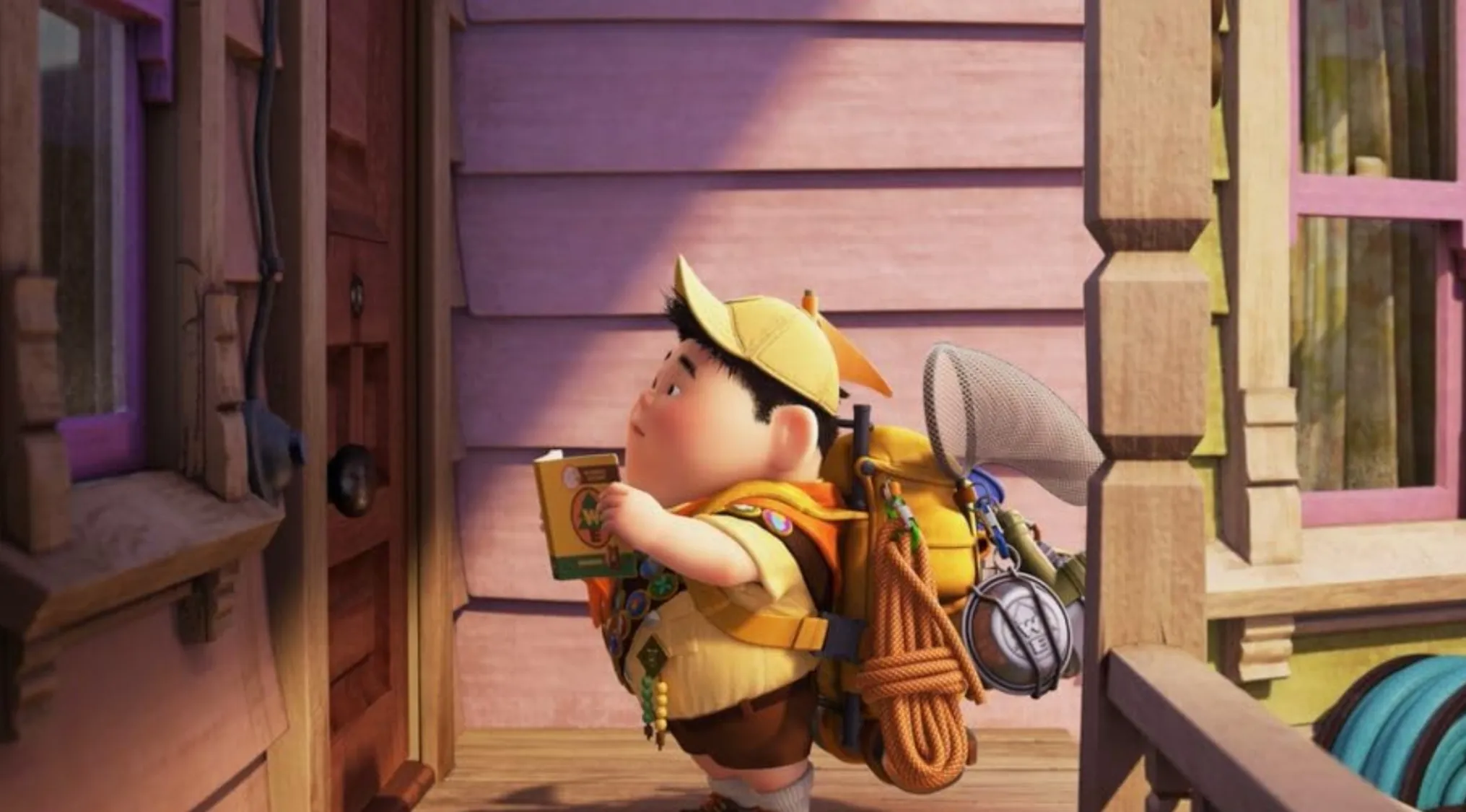 Name the character: Russell, the Wilderness Explorer, standing on a porch with his backpack and handbook, looking up.