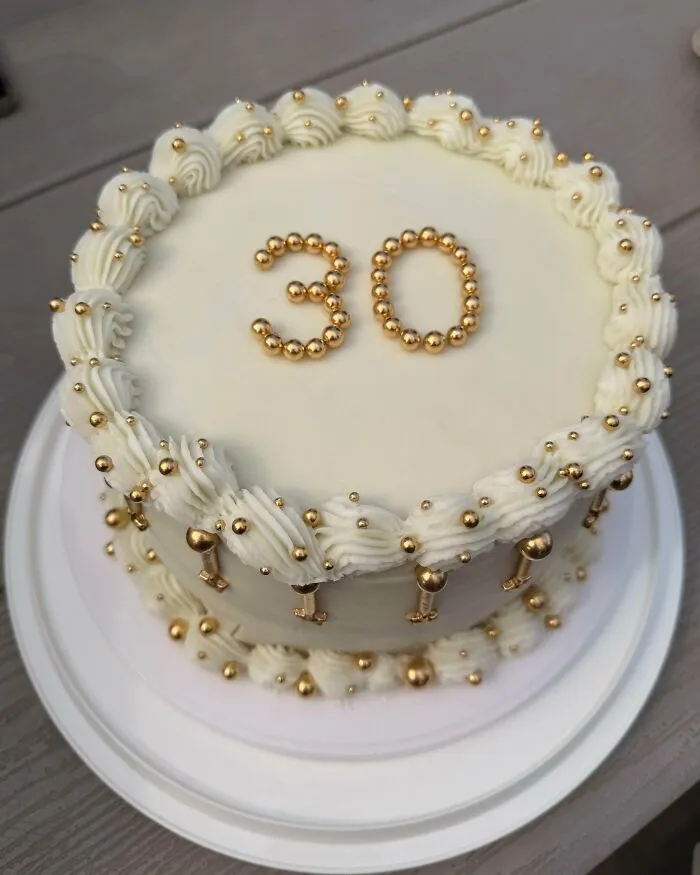 White frosted cake decorated with gold beads number 30 dessert
