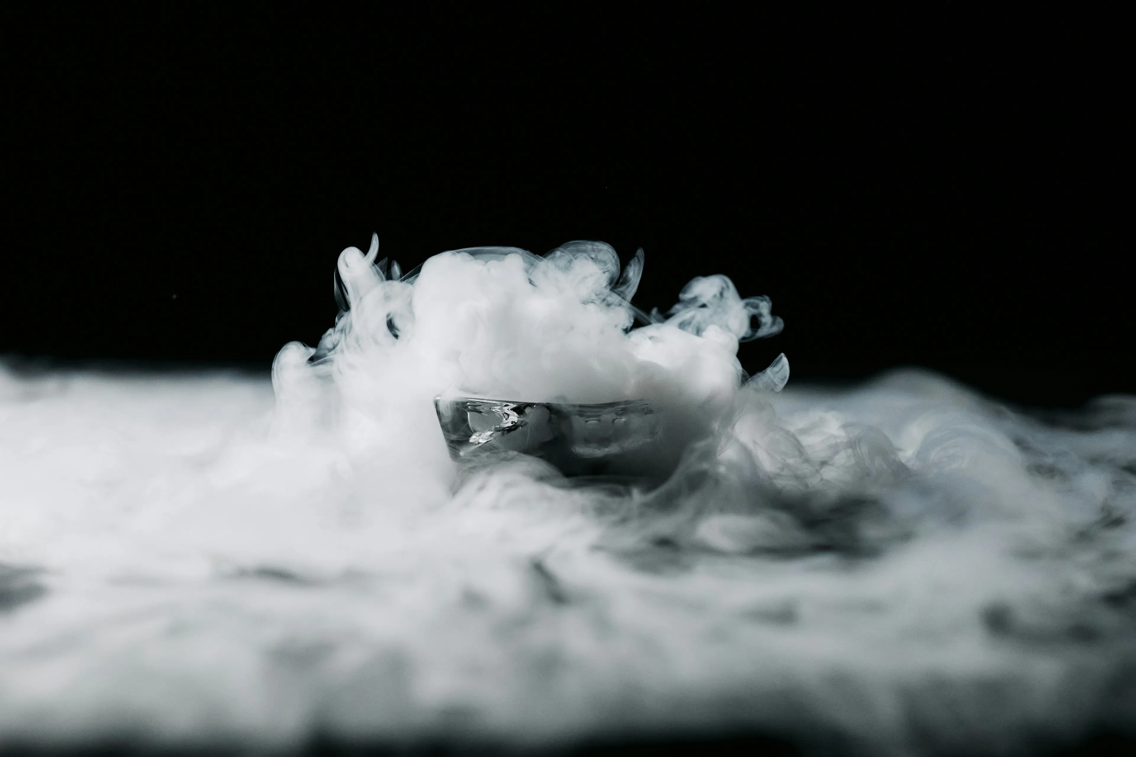 White vapor rises from a container against a dark background, illustrating a substance's transition from solid to gas.