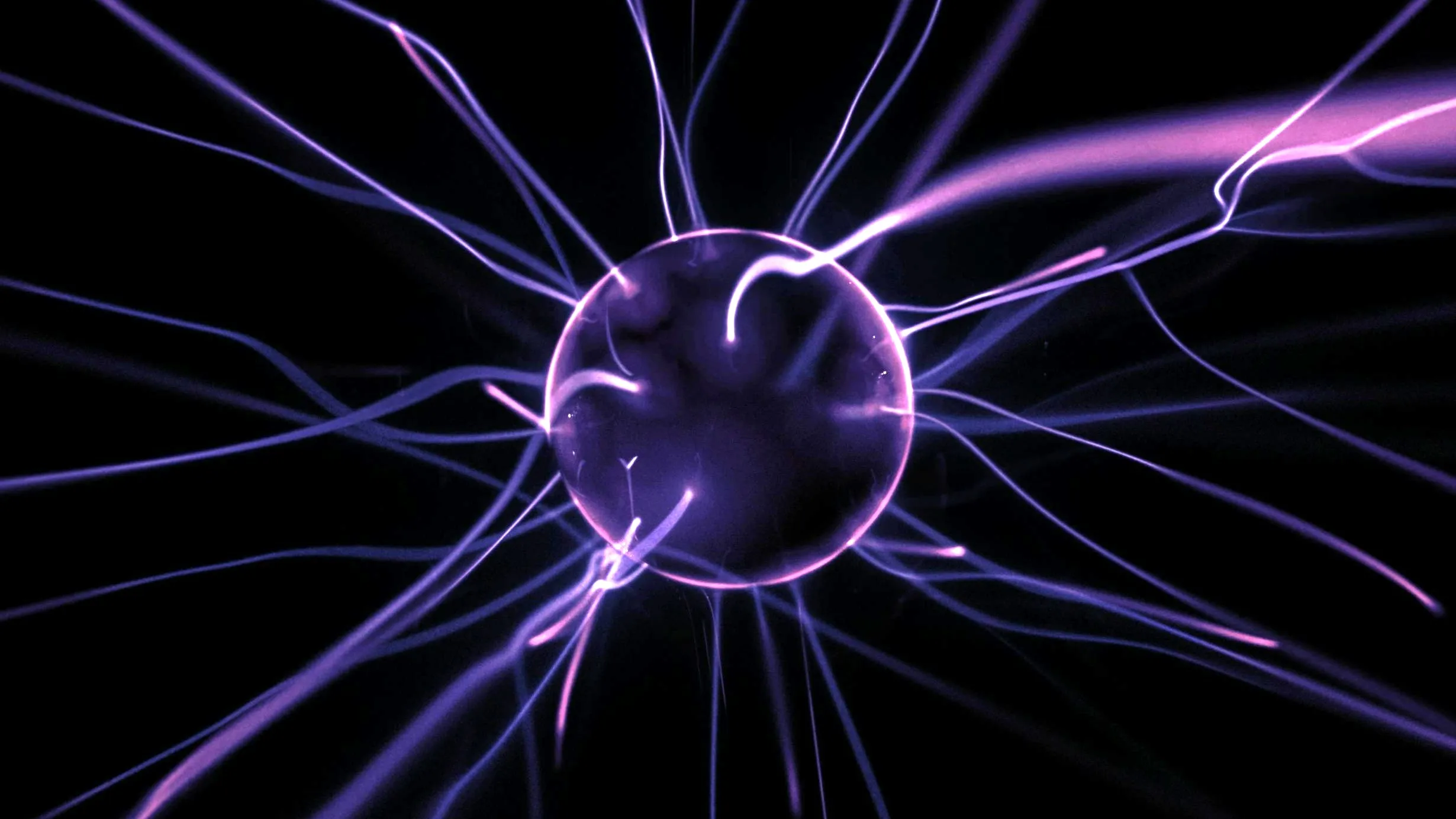 A plasma ball with purple electrical currents reaching out, illustrating the concept of an electrically charged atom.