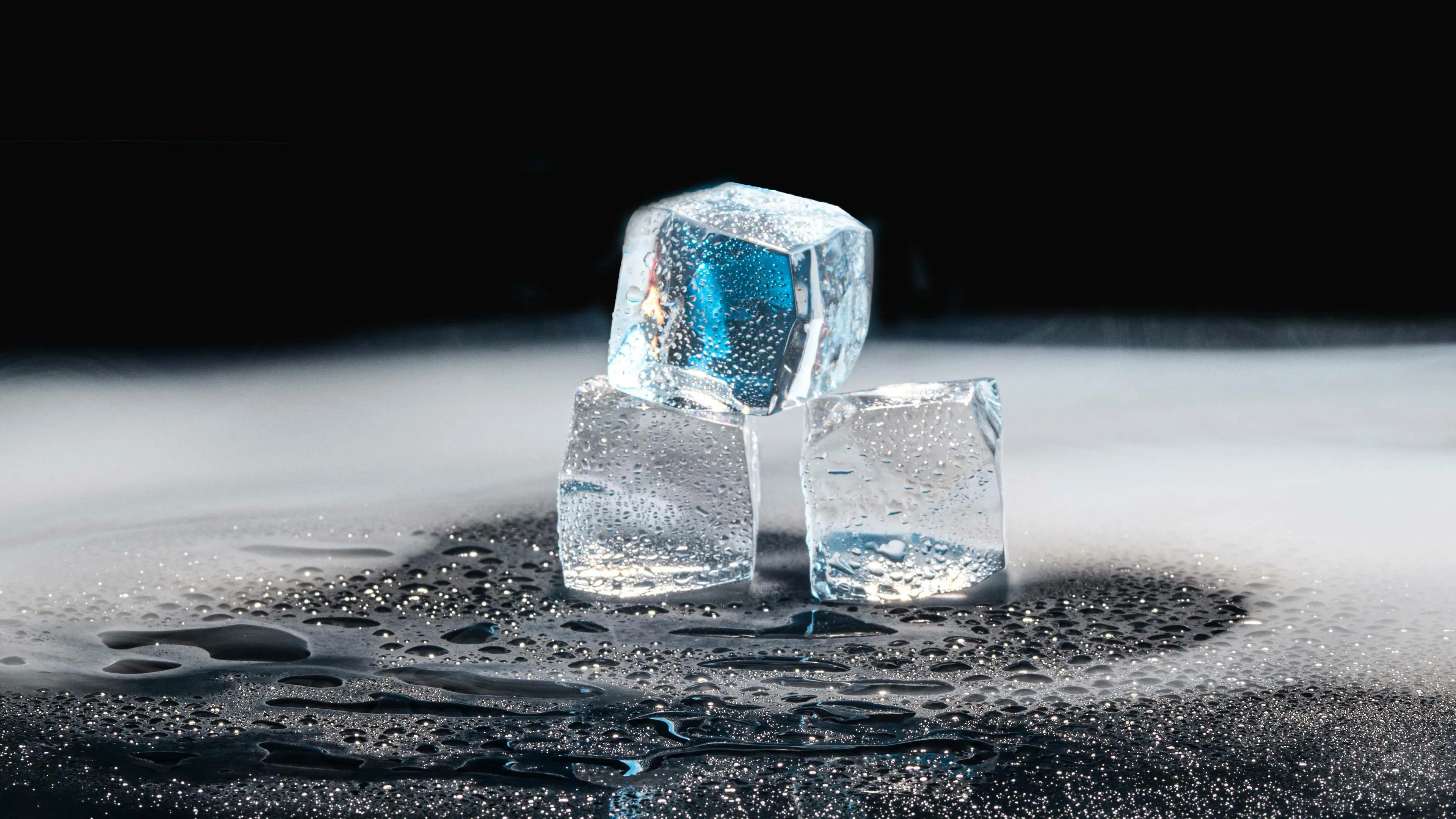 Three ice cubes on a wet surface with mist, illustrating a reaction that absorbs energy and cools the surroundings.