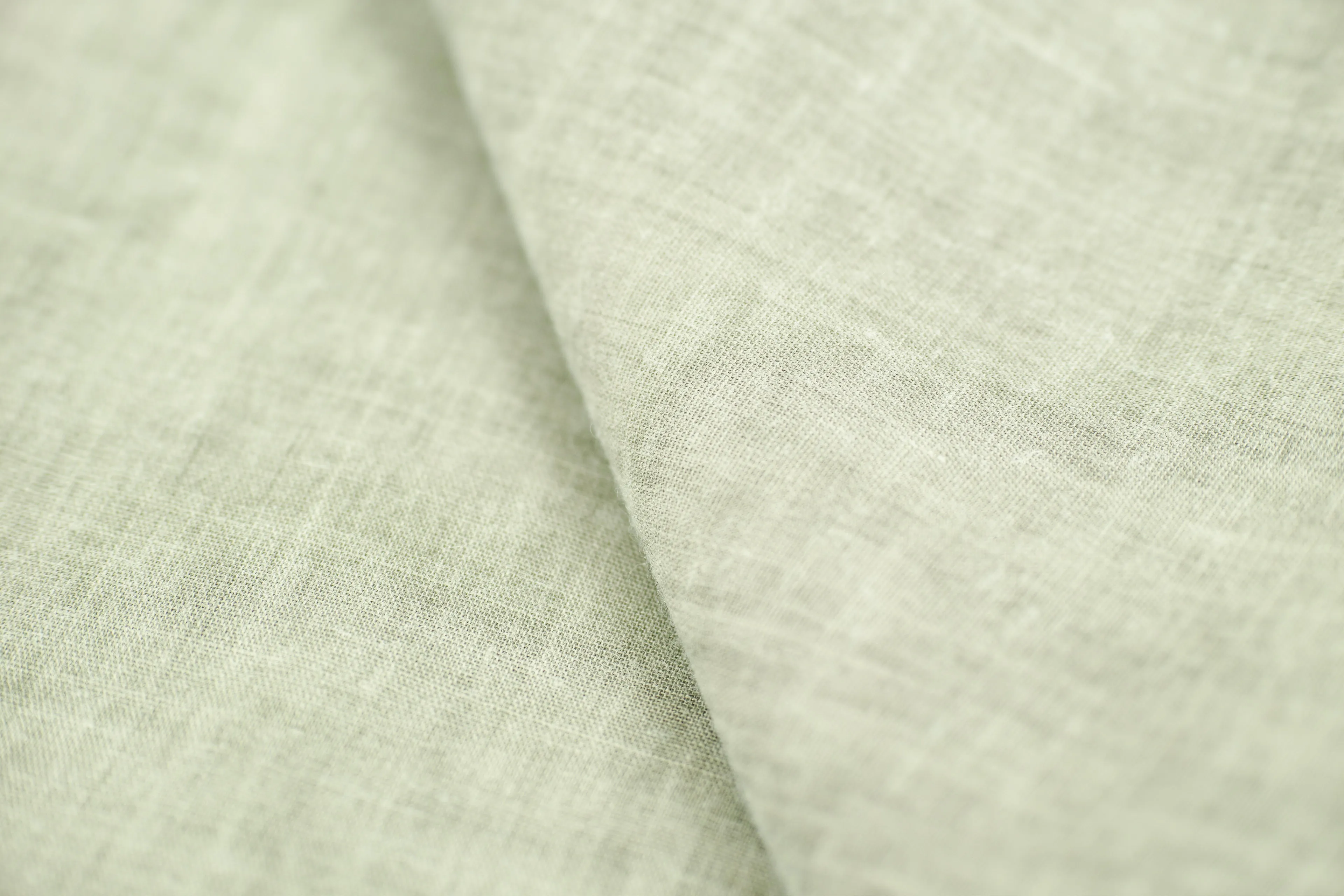 A close-up of light green fabric, evoking the fresh, airy feel of clean linen. Ideal candle scent for living room ambiance.
