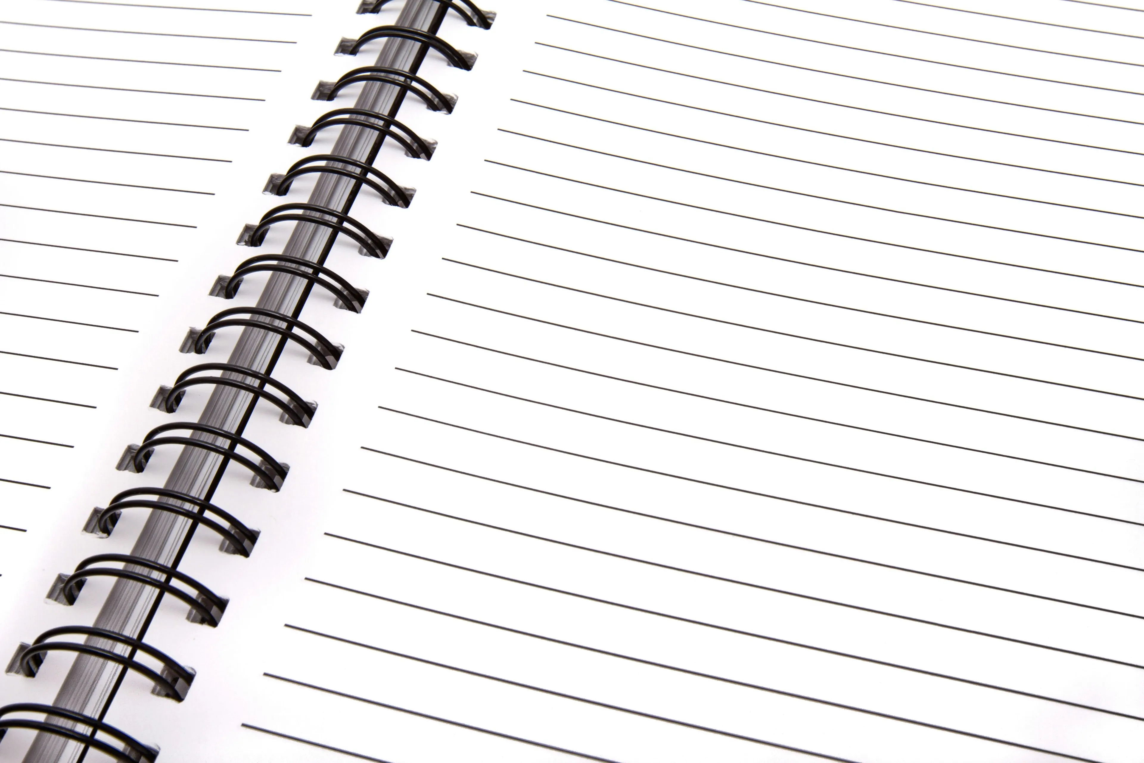 An open spiral notebook, showing clean, lined white pages and the black metal binding.
