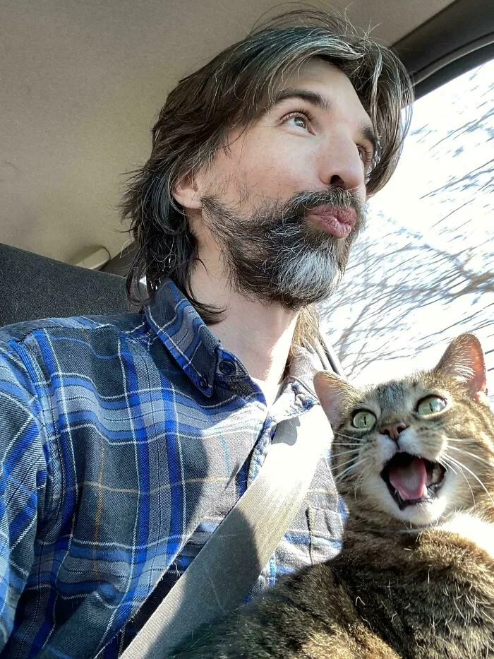 Man and cat both meowing inside a car