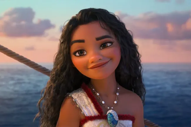 Moana, an animated character, smiles warmly with a sea backdrop. She wears a traditional outfit and a shell necklace.