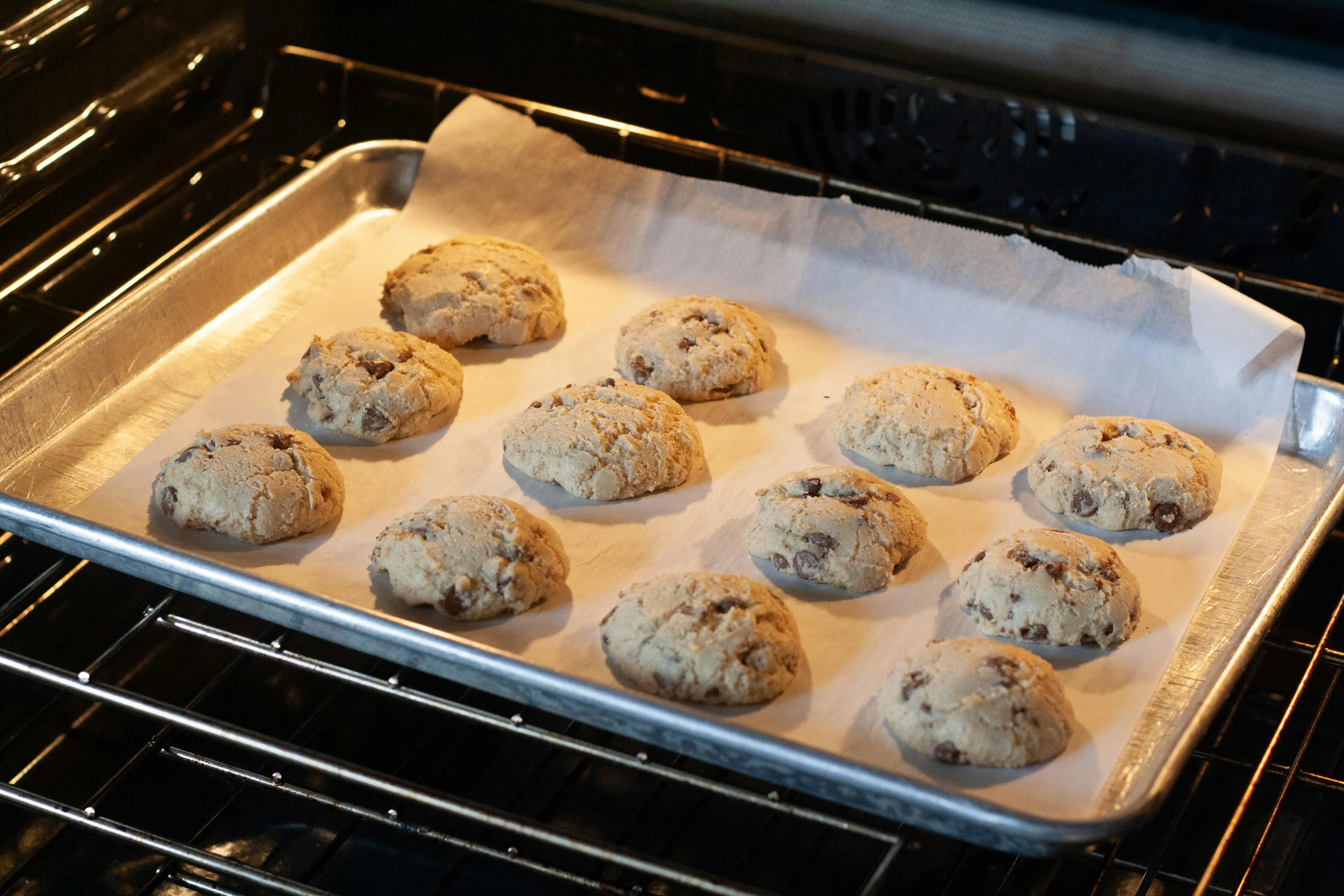 A baking sheet of homemade cookies, unbaked, on parchment paper, sitting on an oven rack. Perfect for a picnic!