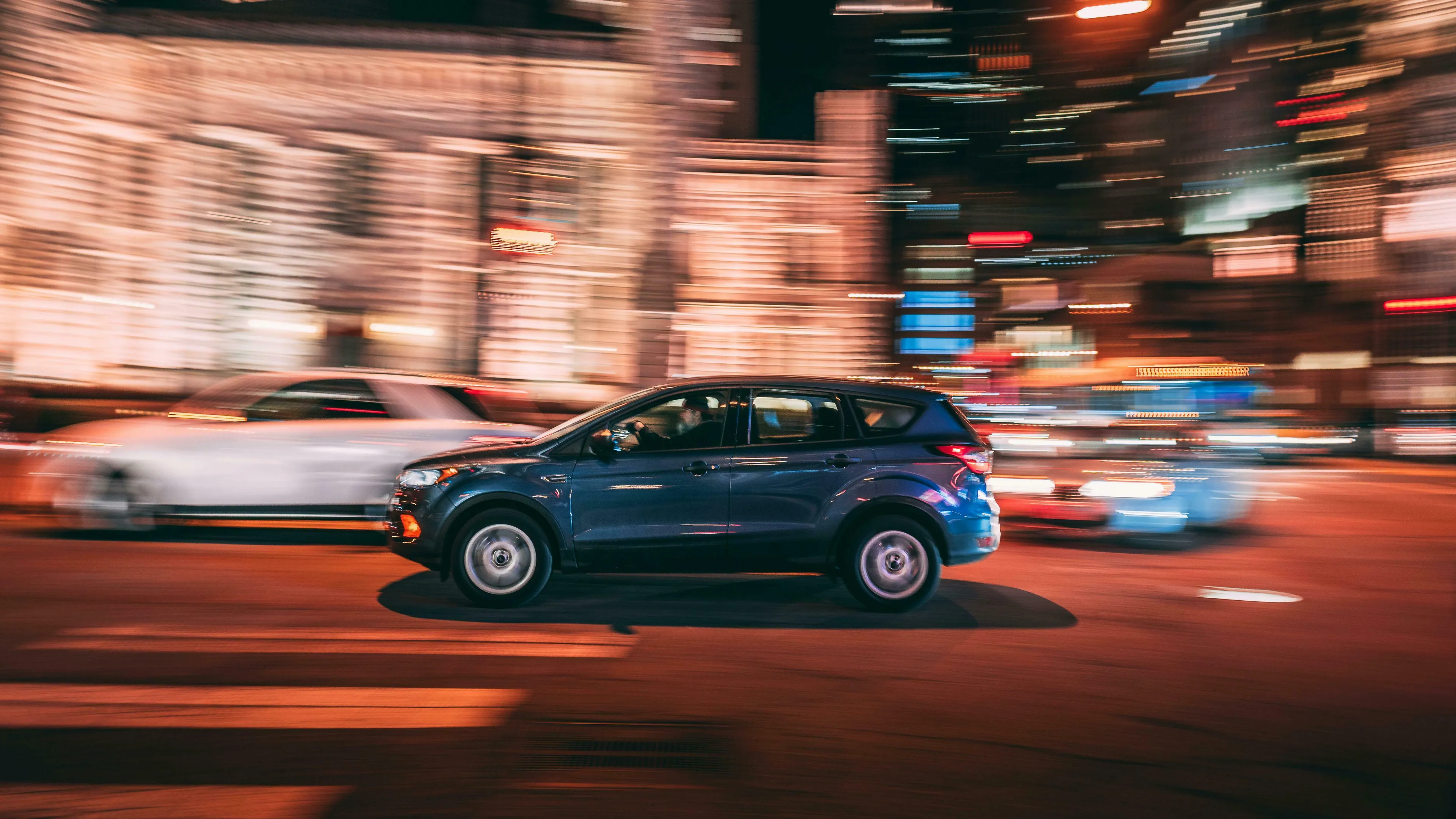 A blue car driving at night with motion blur. Great British vocabulary quiz, car parts, boot.