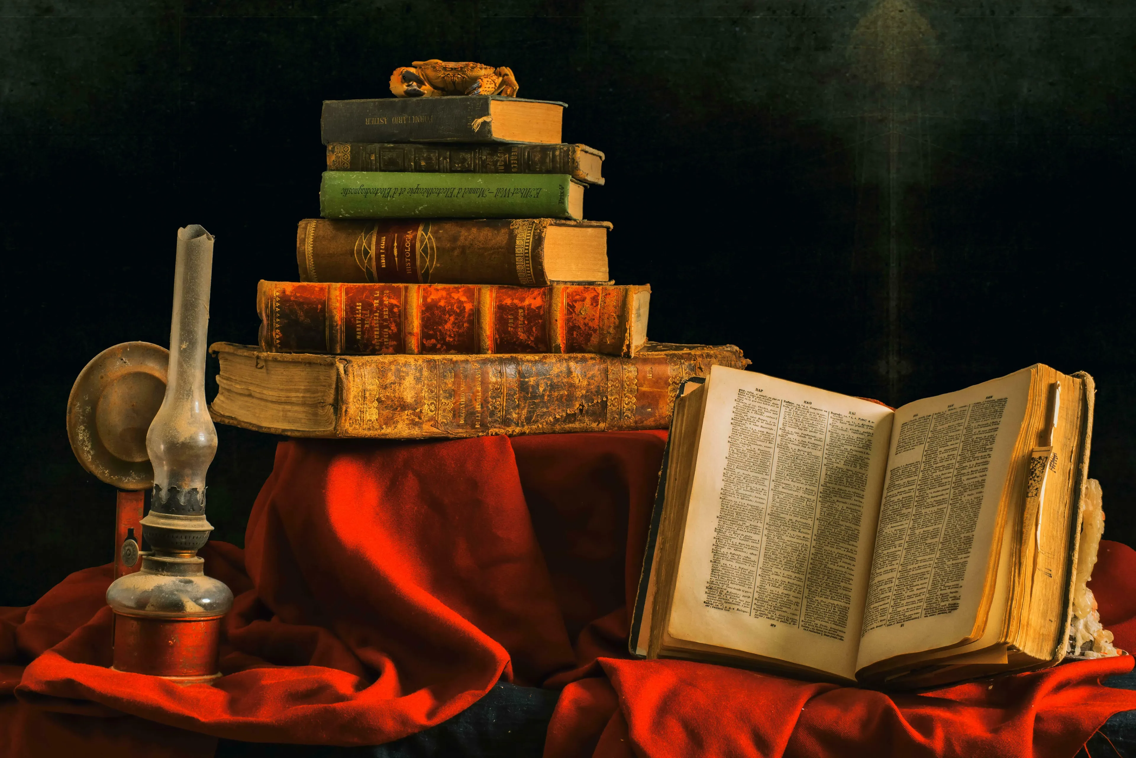 A still life of antique books, an open book, and an oil lamp on a red cloth for a general knowledge quiz.