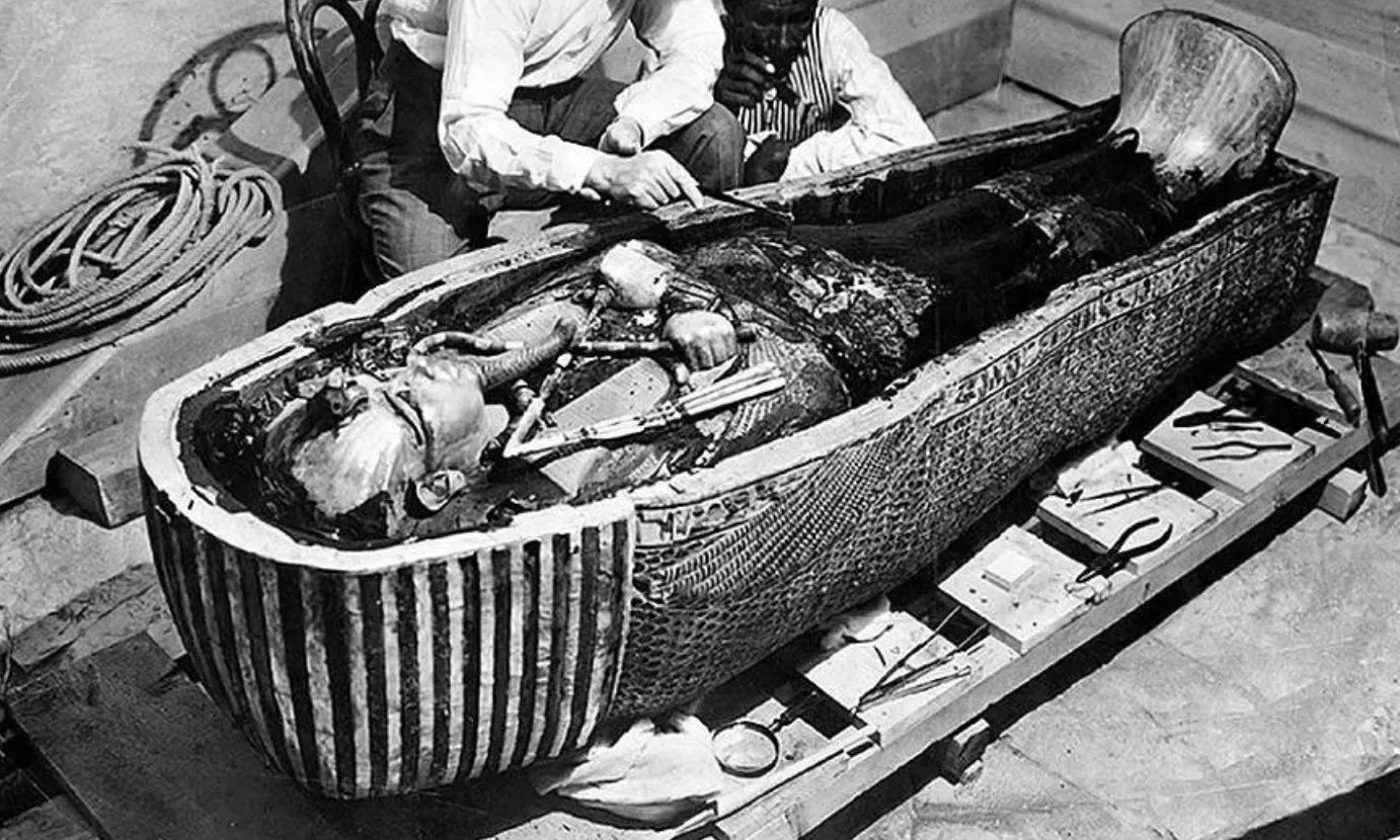 Black and white photo of archaeologists examining the mummy of Pharaoh Tutankhamun in its intact tomb. Difficult General Knowledge Quiz.