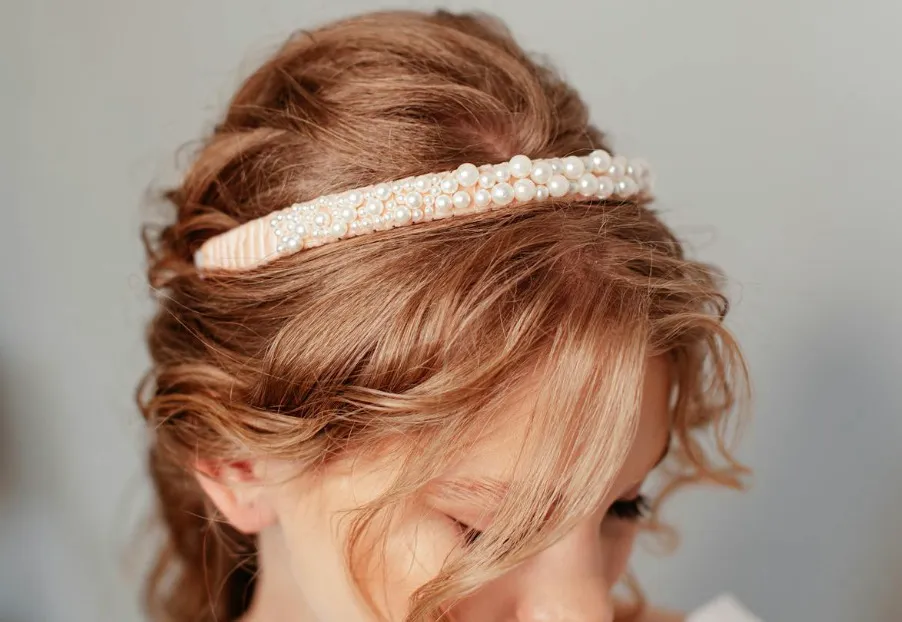 Close-up of a blonde woman wearing a beautiful pearl headband, a popular Y2K accessory, showcasing a stylish hairstyle.