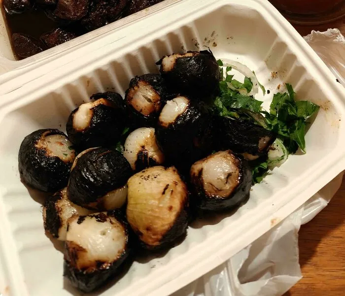Charred, blackened onions in a white takeout container representing questionable food combos.