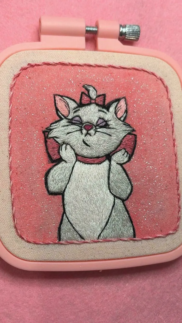 Cute embroidered cat character on a pink glittery background from creative embroidery projects.