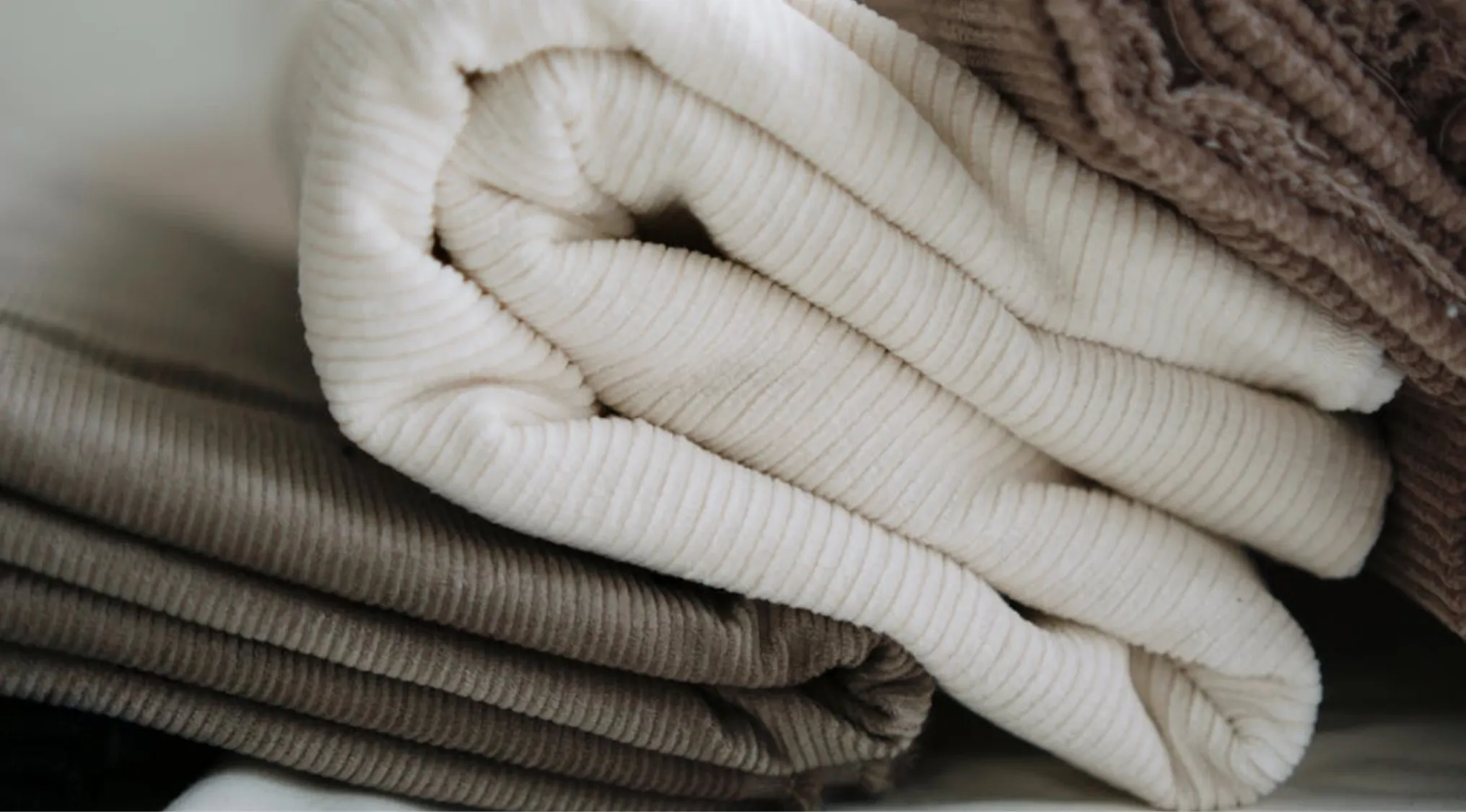 Folded corduroy fabrics in cream, beige, and brown, illustrating fabric choice and care in Home Economics.