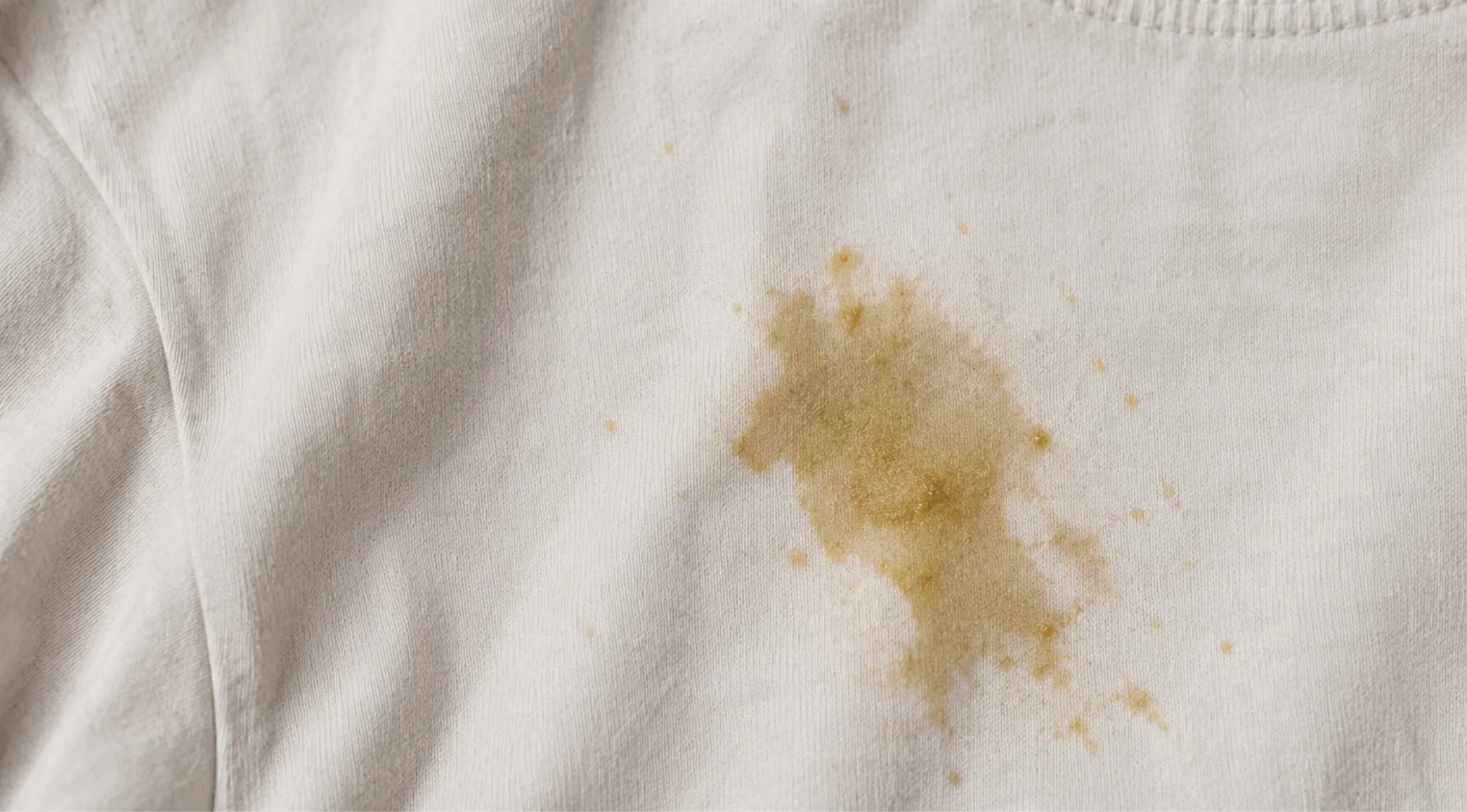 A close-up of a noticeable fresh stain on a white shirt, demonstrating the need for Home Economics tips to remove it.