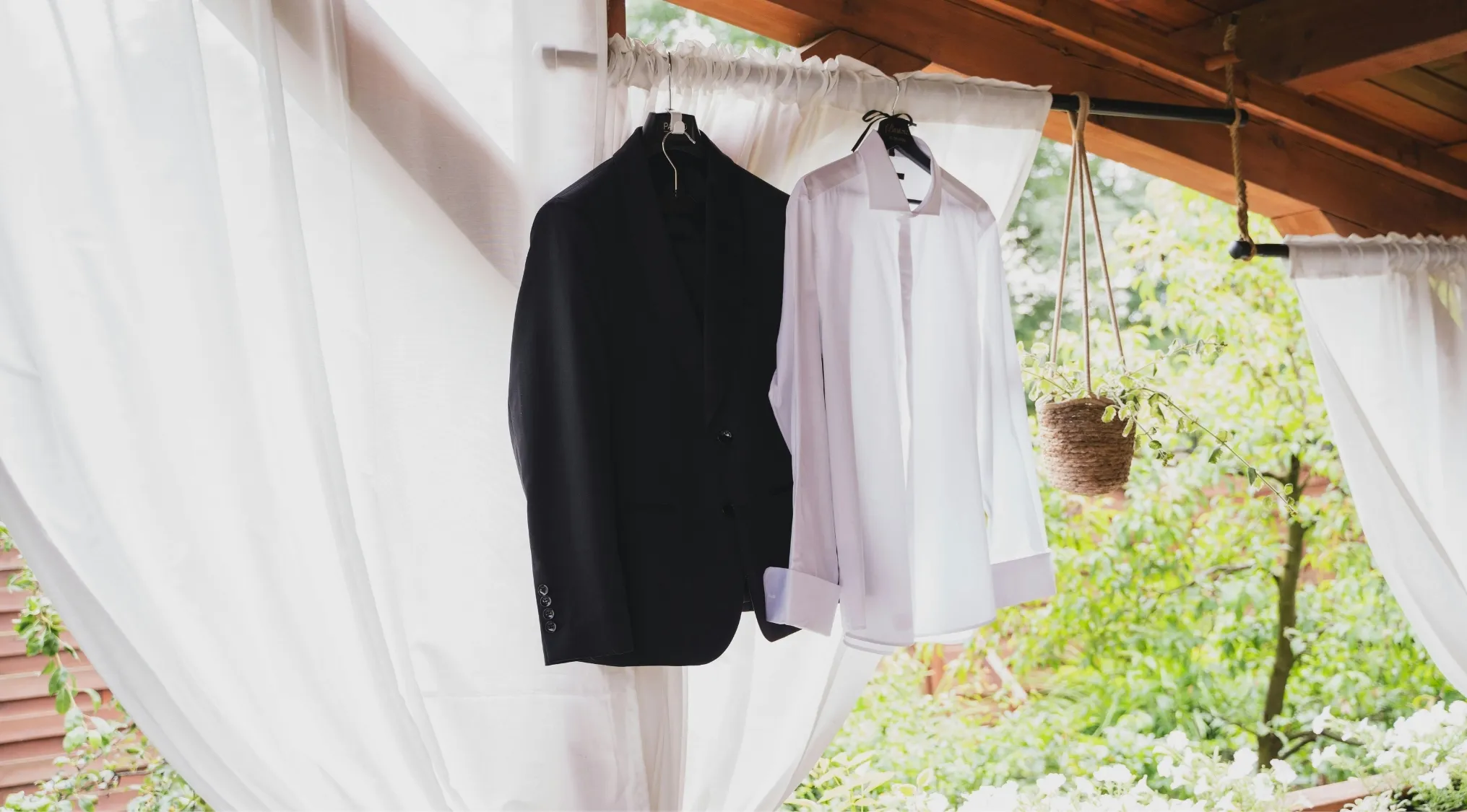 A black suit jacket and a white dress shirt hang side-by-side. Home Economics suggests separating lights and darks when doing laundry.