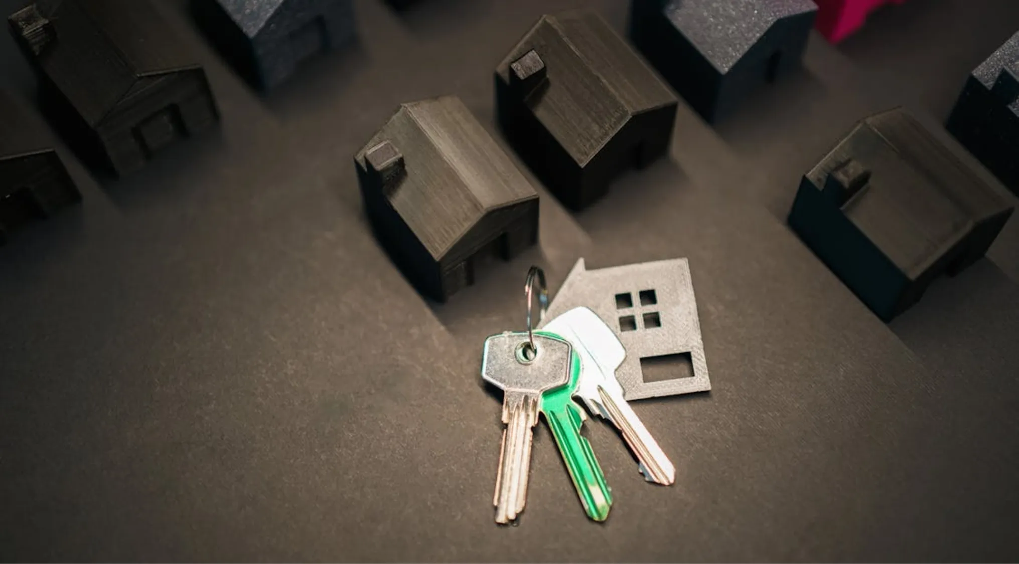 Keys and miniature houses on a dark surface, symbolizing apartment renting and home economics. What is a lease?