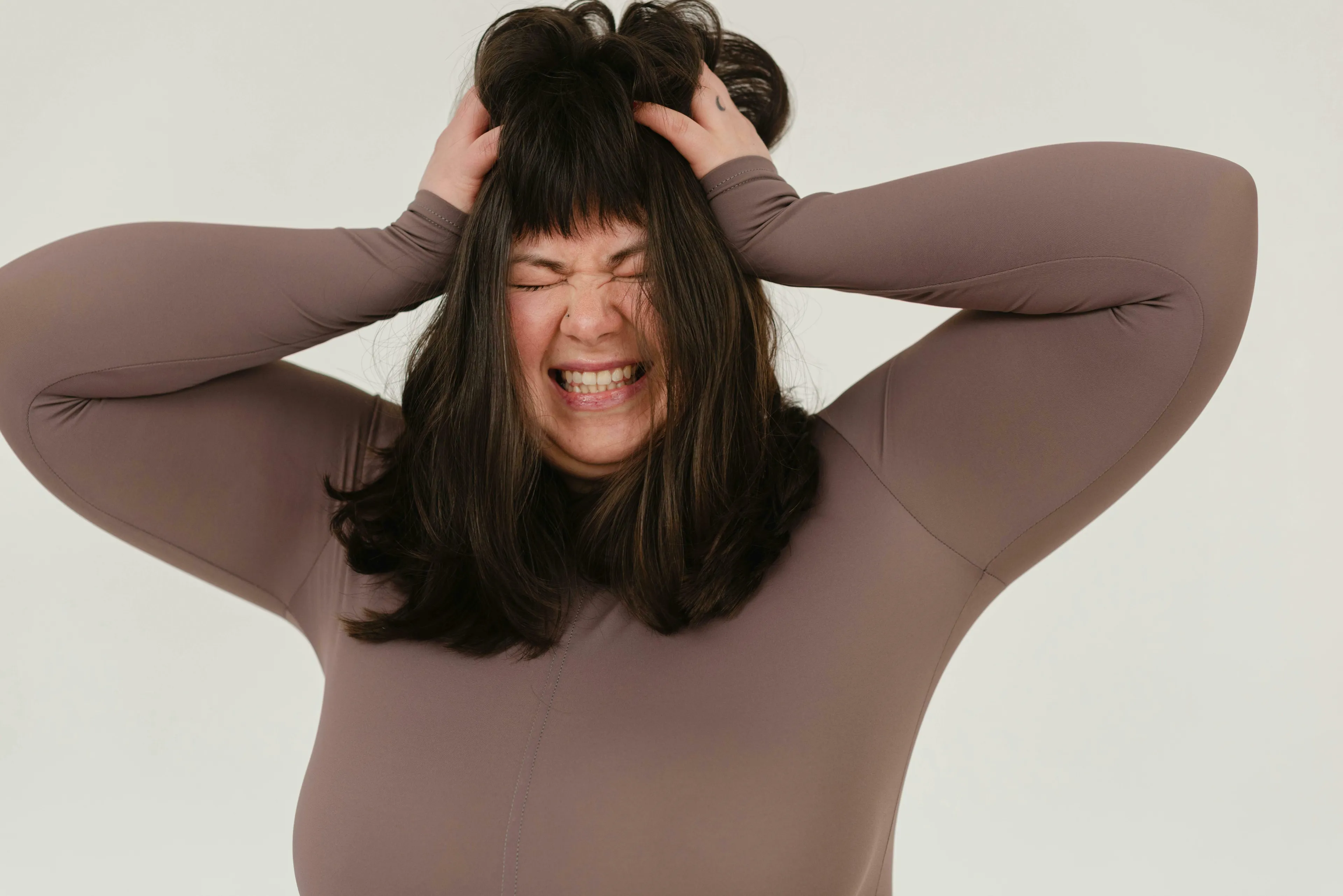 A woman clenches her eyes shut and pulls her hair in frustration. What do you find hardest to tolerate in other people?