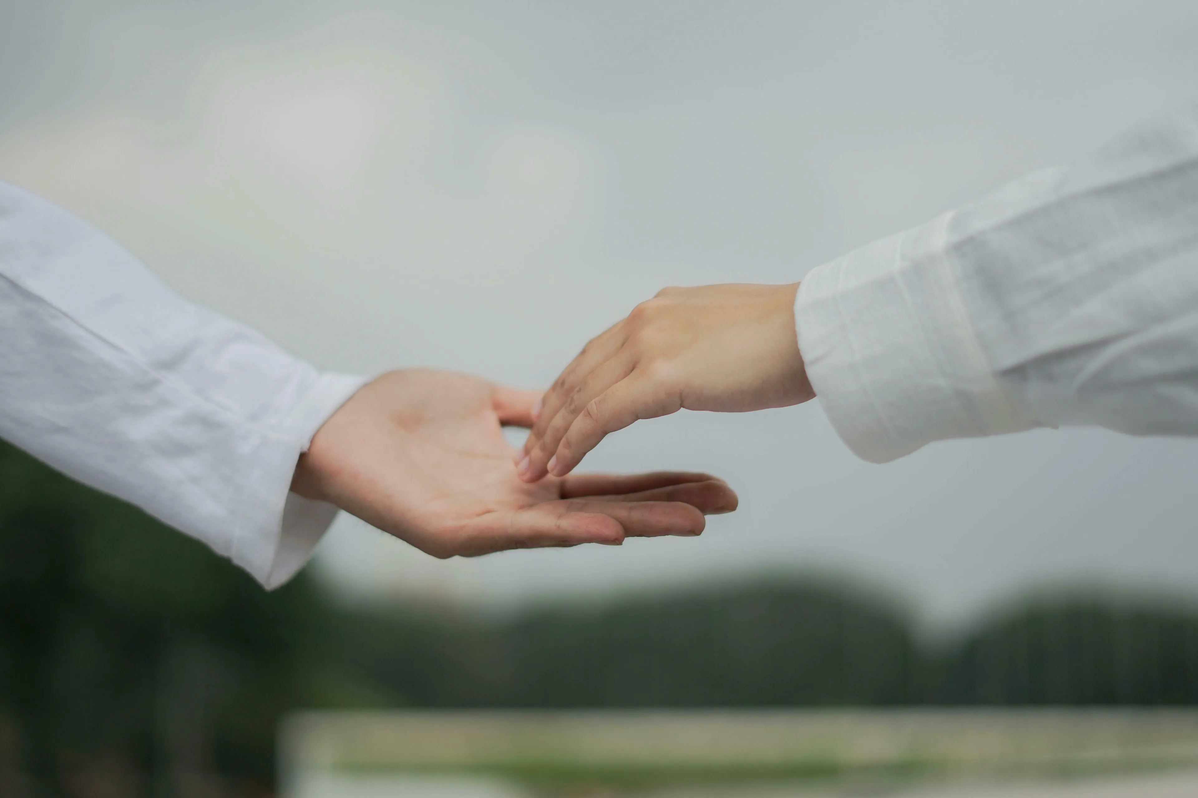 Two hands, one outstretched with palm up, the other reaching towards it, symbolizing asking for help.