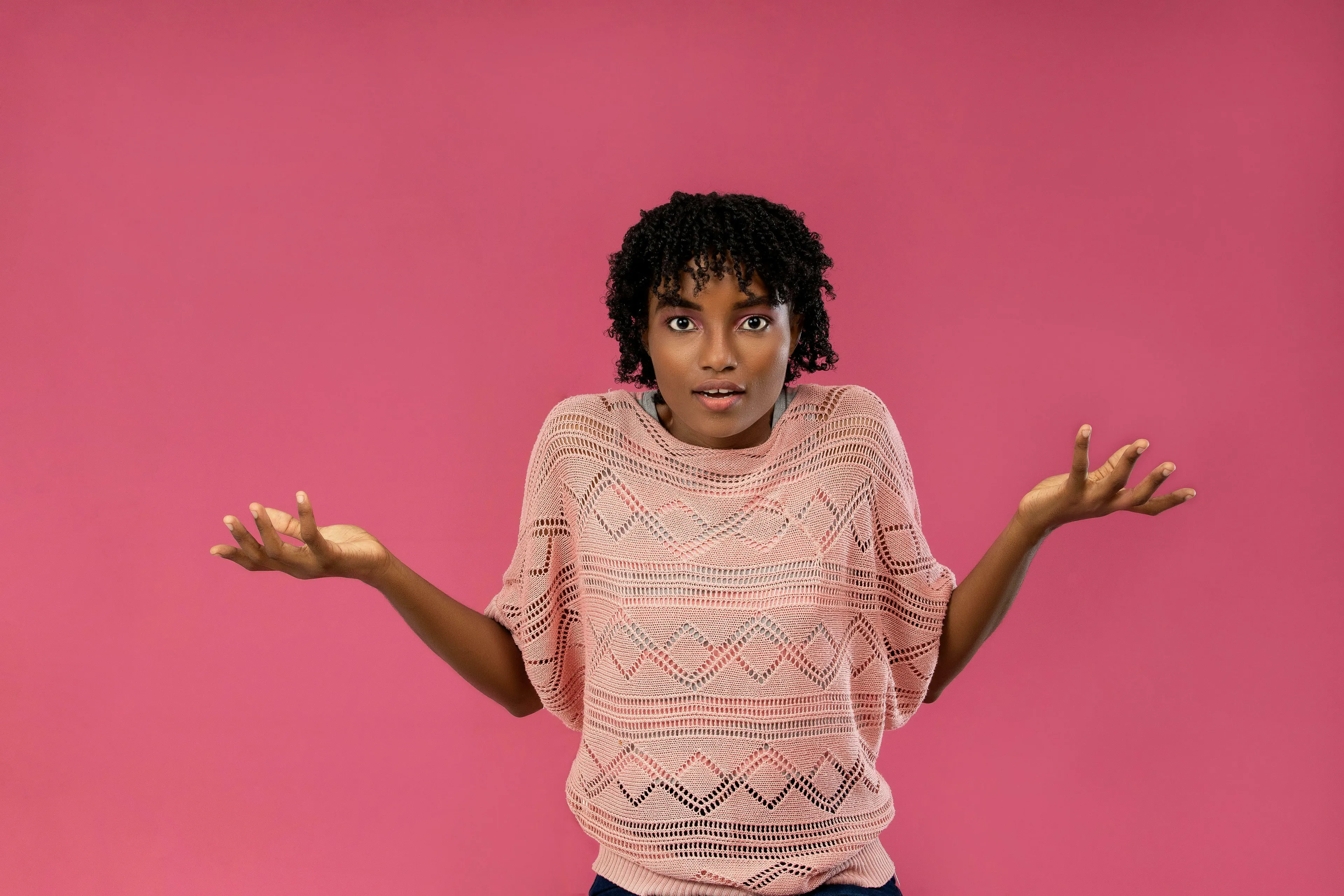 A confused woman shrugging against a pink background, questioning how unique are you.